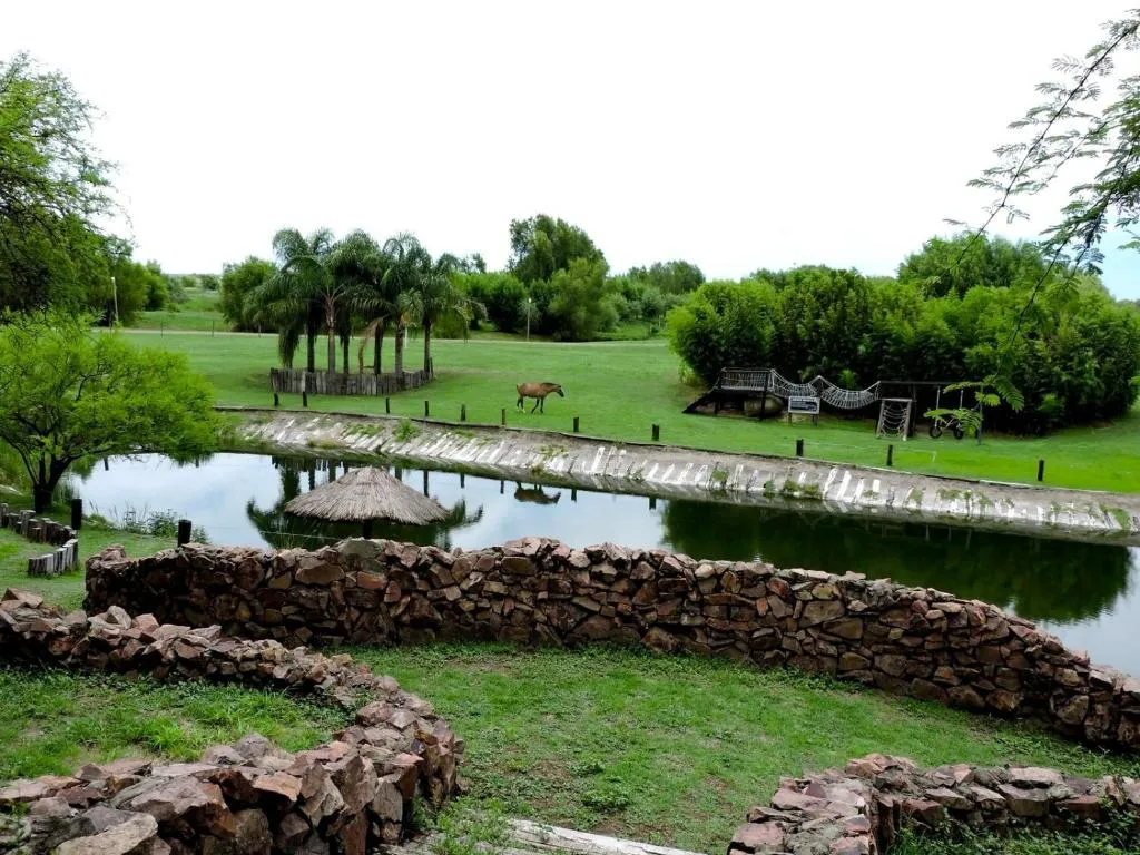 Paisaje con agua, palmeras y espacios verdes junto a un muro de piedra
