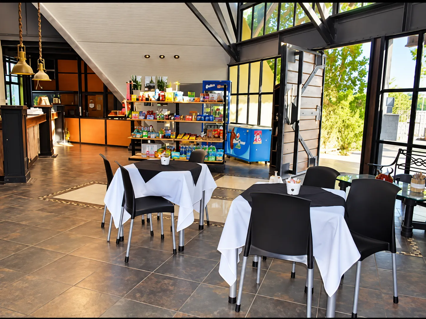 Salón luminoso con mesas, sillas y estantería con productos