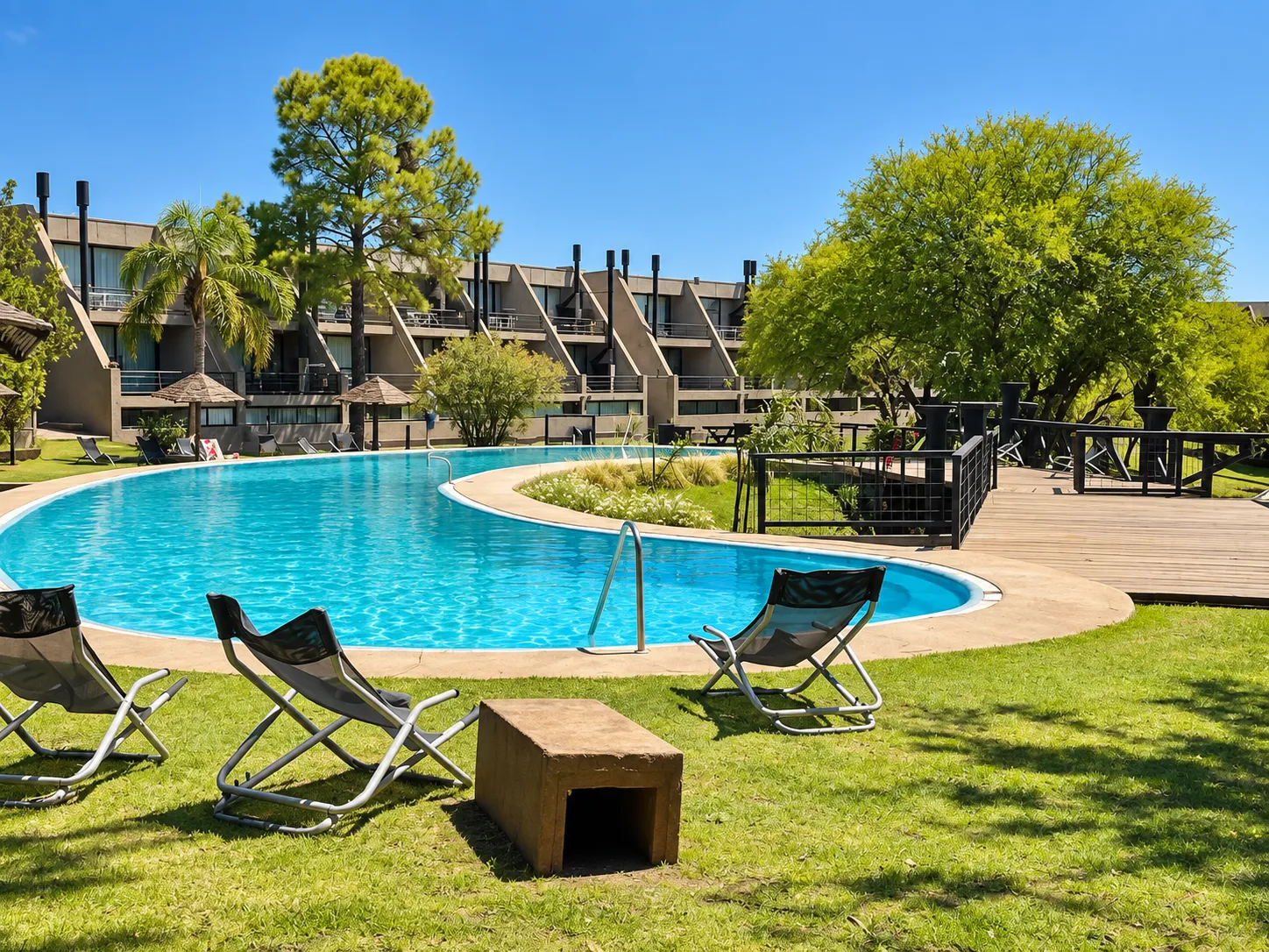 Piscina exterior con jardín, reposeras y terraza de madera